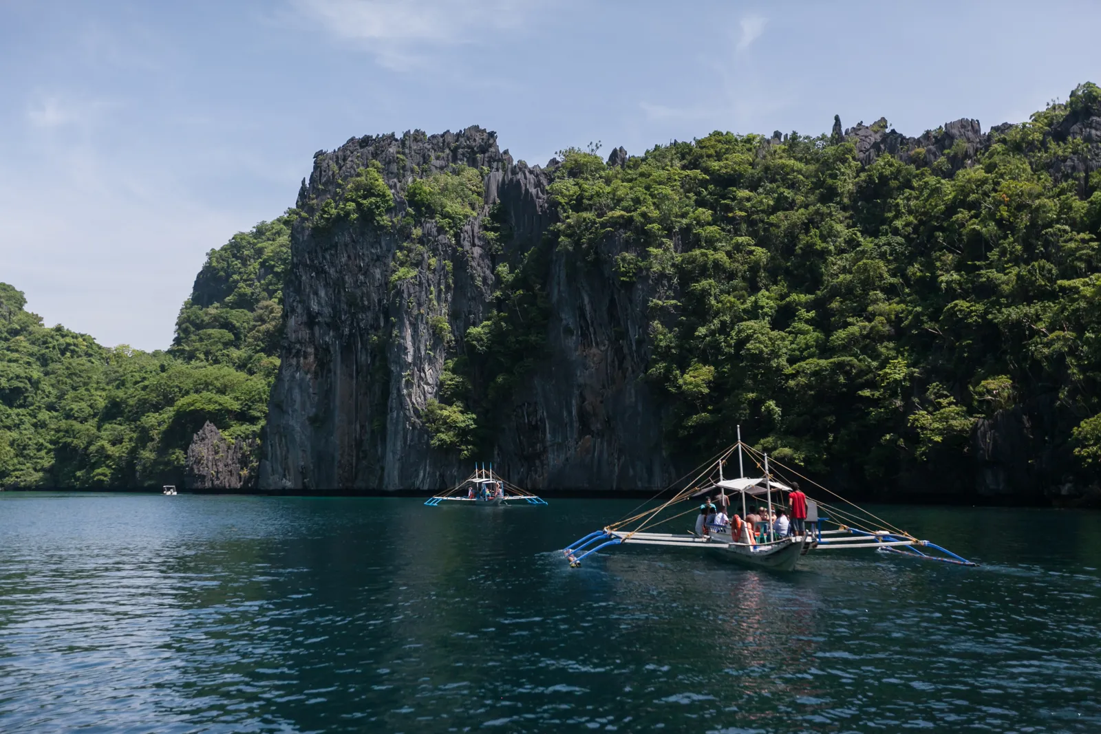 Quand partir aux Philippines ? Meilleure période et climat mois par mois Bateau en bois dans un lagon bleu au pied des falaises calcaires d'El Nido, à Palawan