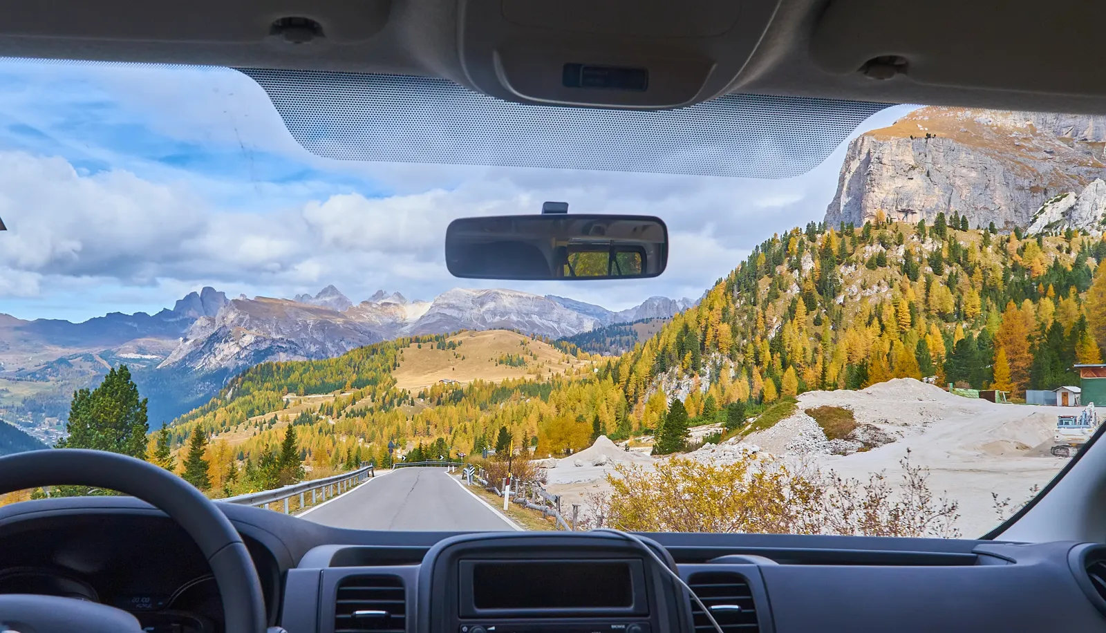 Road trip : préparer son itinéraire, son budget et sa location Route de montagne sinueuse dans les Alpes vue depuis le pare-brise en road trip