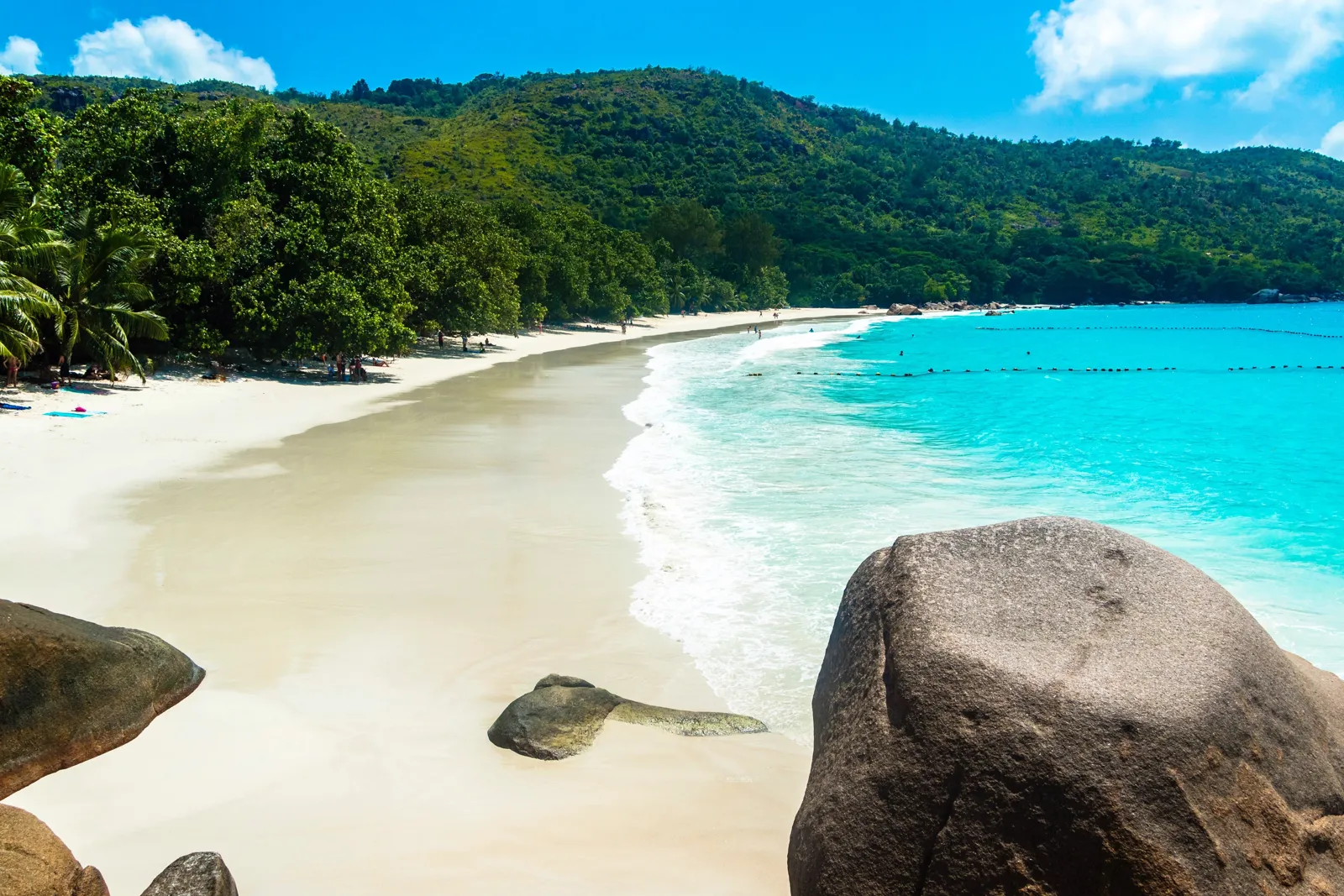 Quand partir aux Seychelles ? Meilleure période et climat mois par mois Plage de Praslin bordée de végétation sous un ciel bleu
