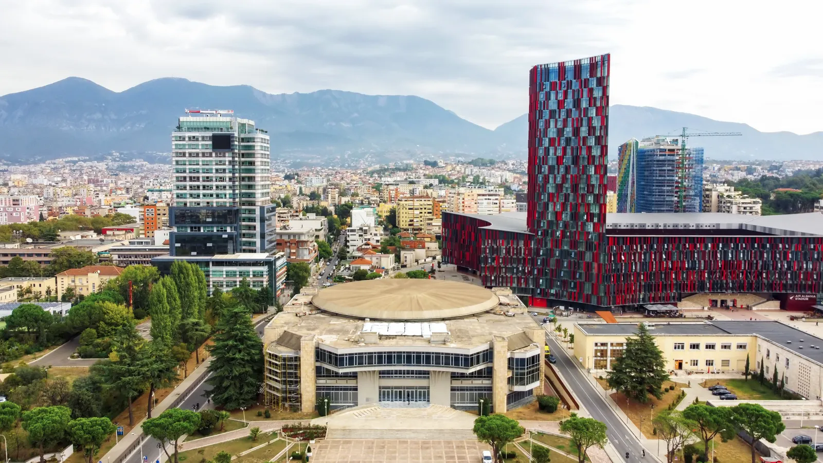 Que faire à Tirana : incontournables, excursions et formalités Vue aérienne de Tirana avec le lac artificiel et les montagnes au loin