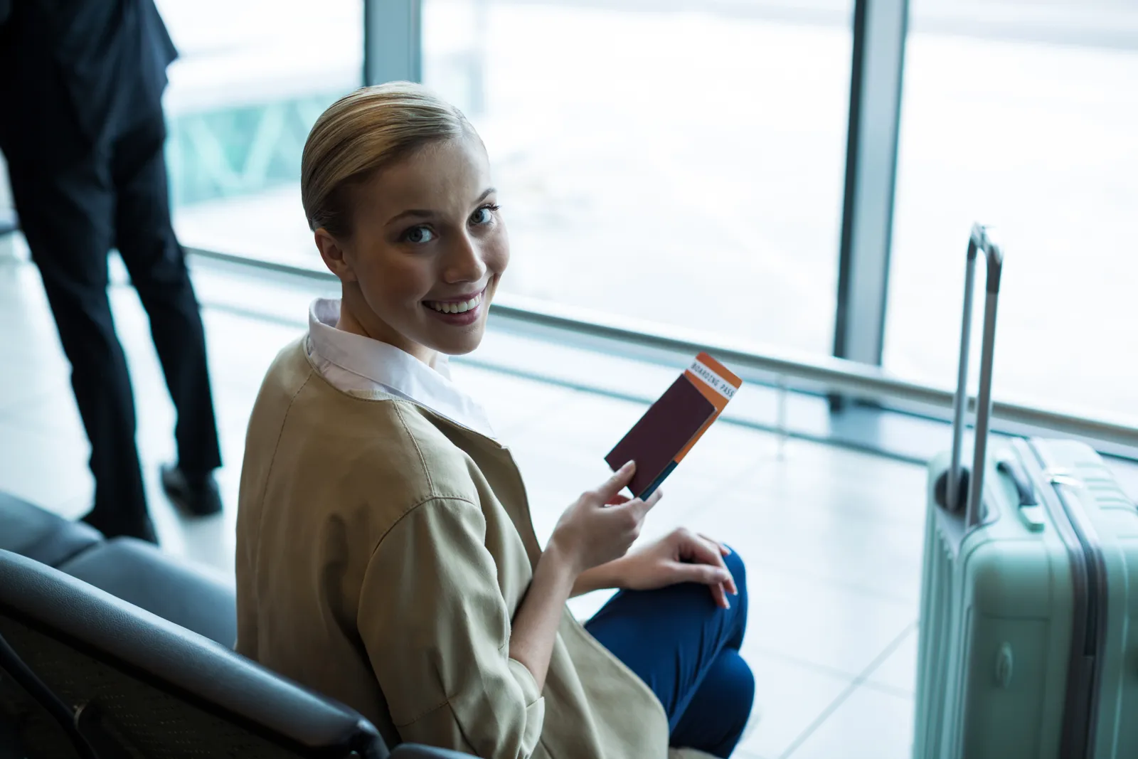Voyage de dernière minute pas cher : mode d'emploi Voyageuse avec passeport et carte d'embarquement en salle d'attente d'aéroport