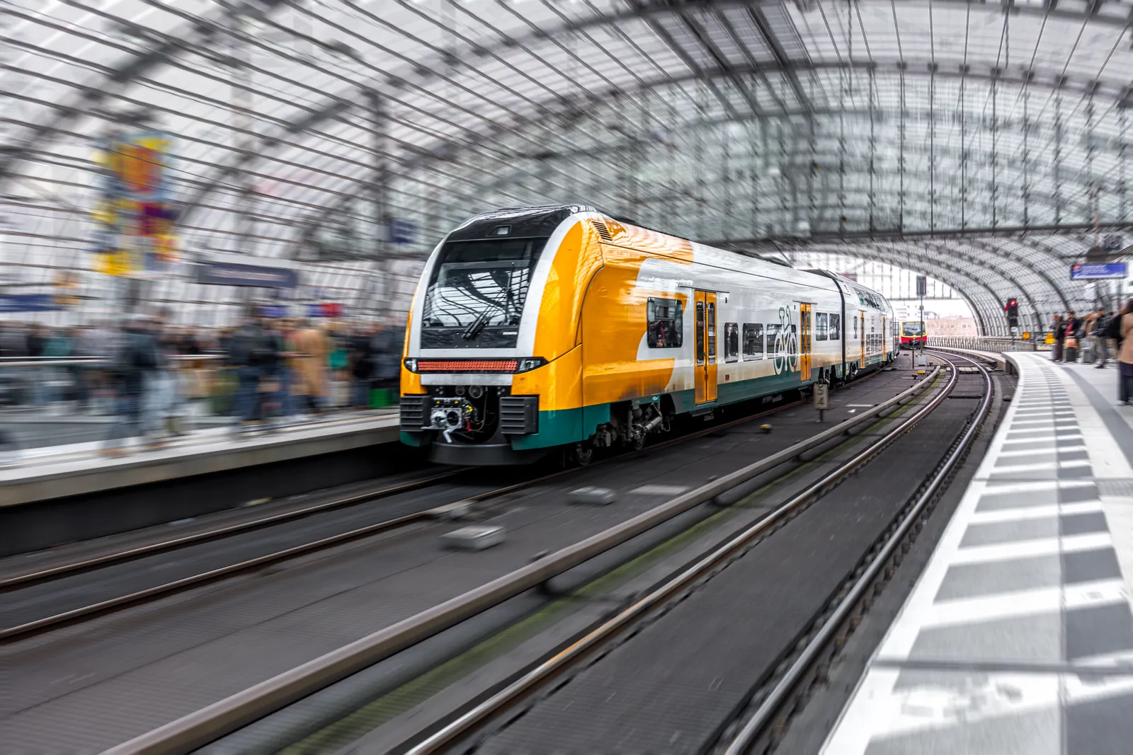 Train à grande vitesse arrivant en gare devant des voyageurs sur le quai